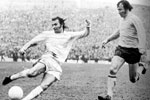 Dennis Tueart crosses under challenge from Bob McNab